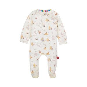 A baby footed sleeper in an off-white fabric with a playful print of cartoon animals and trees in soft pastel colors, featuring a colorful striped inner neck trim and a small red tag on the side.