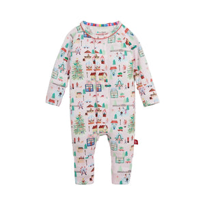 A baby long-sleeve convertible one-piece jumpsuit with an all-over winter village print on a white background. The print features colorful houses, Christmas trees, and skiers, with a striped collar.